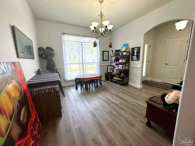 playroom with a textured ceiling, arched walkways, a chandelier, and wood finished floors