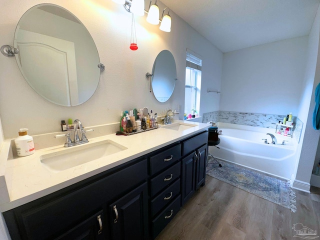 bathroom with double vanity, a bath, a sink, and wood finished floors