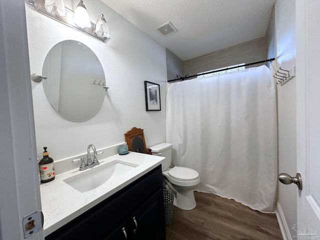 bathroom featuring a textured ceiling, toilet, wood finished floors, vanity, and visible vents