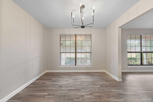 unfurnished dining area featuring hardwood / wood-style floors, a notable chandelier, and a textured ceiling