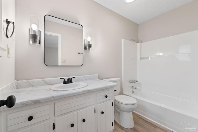 full bathroom with bathing tub / shower combination, hardwood / wood-style floors, a textured ceiling, toilet, and vanity