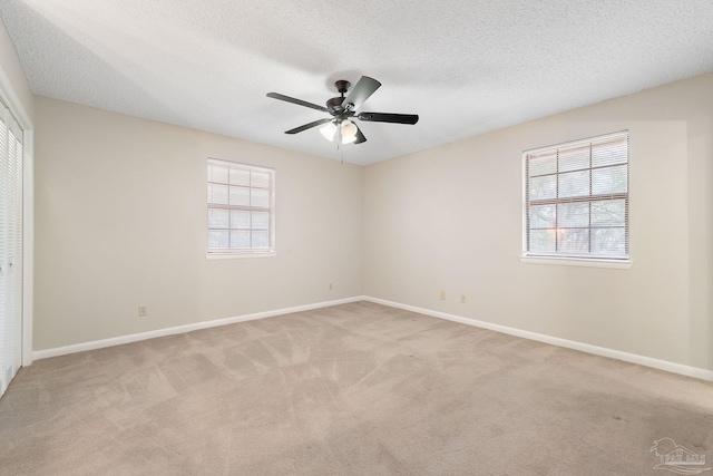 unfurnished room featuring a textured ceiling, light colored carpet, and ceiling fan