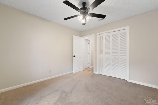 unfurnished bedroom featuring a textured ceiling, carpet floors, a closet, and ceiling fan