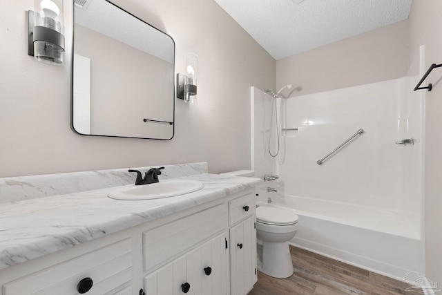 full bathroom with vanity, a textured ceiling, bathing tub / shower combination, wood-type flooring, and toilet