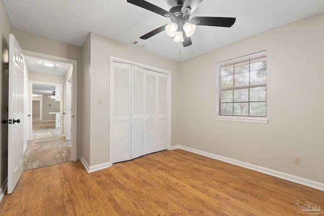 unfurnished bedroom featuring a textured ceiling, light wood-type flooring, a closet, and ceiling fan