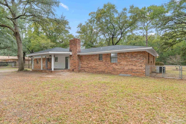 back of property with central AC unit and a lawn