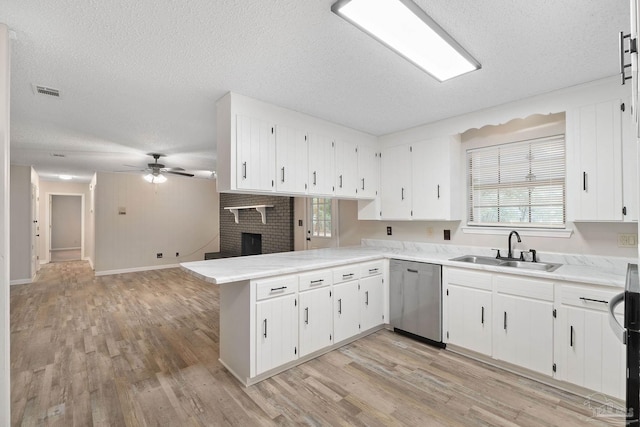 kitchen featuring sink, stainless steel dishwasher, kitchen peninsula, plenty of natural light, and a fireplace