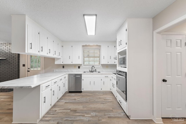 kitchen featuring kitchen peninsula, appliances with stainless steel finishes, white cabinetry, and sink