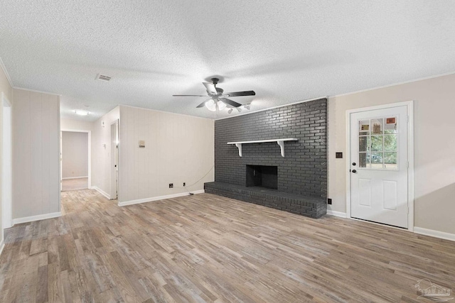 unfurnished living room with a textured ceiling, ceiling fan, light hardwood / wood-style floors, and a fireplace