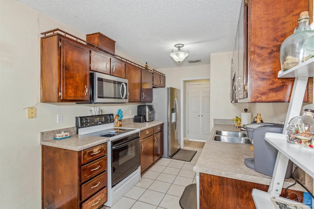 kitchen with appliances with stainless steel finishes, a textured ceiling, light tile patterned floors, and sink