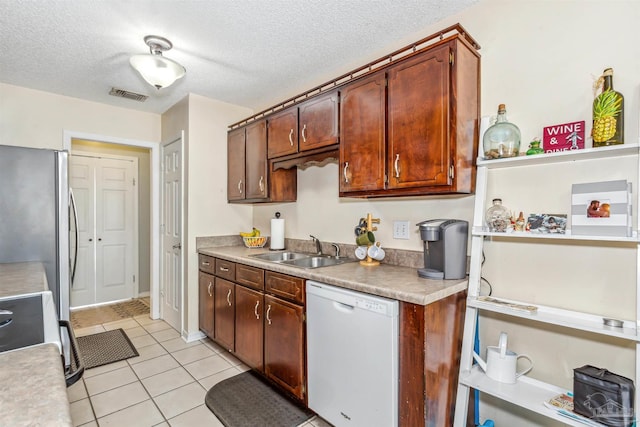 kitchen featuring sink, stainless steel fridge, white dishwasher, a textured ceiling, and light tile patterned floors