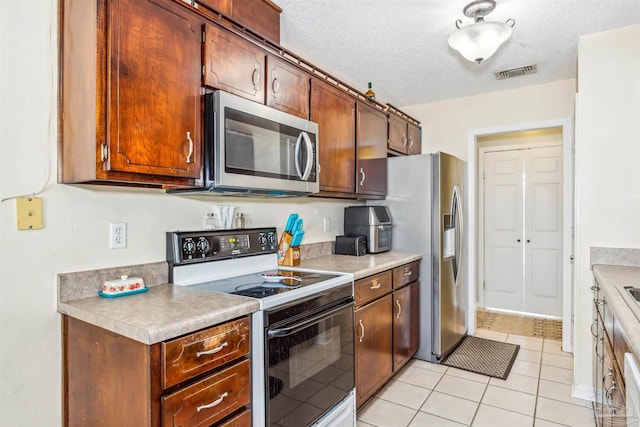 kitchen featuring appliances with stainless steel finishes, a textured ceiling, and light tile patterned floors