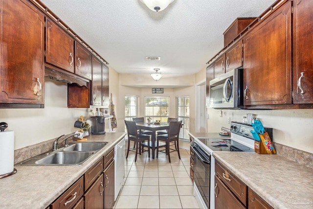 kitchen featuring light tile patterned floors, a textured ceiling, stainless steel appliances, and sink