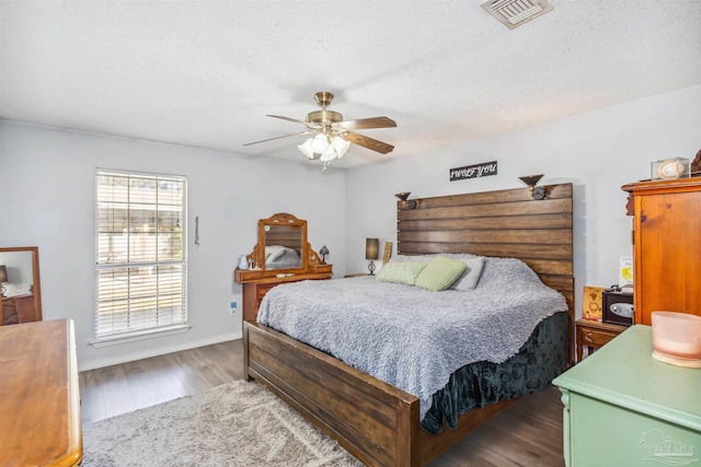 bedroom with a textured ceiling, ceiling fan, and dark wood-type flooring