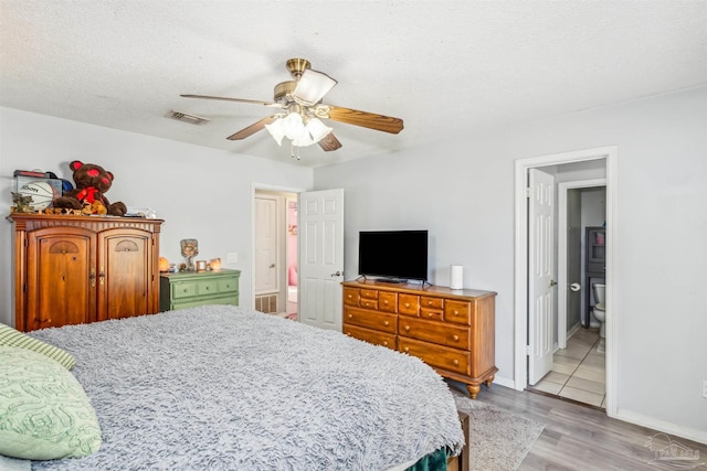 bedroom featuring ceiling fan, light hardwood / wood-style floors, a textured ceiling, and connected bathroom