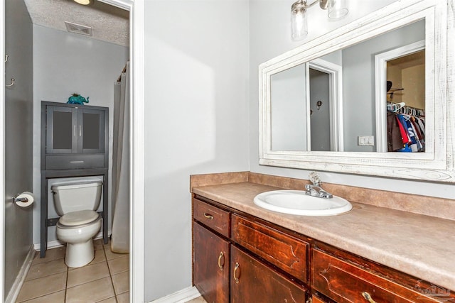 bathroom with tile patterned flooring, vanity, toilet, and a textured ceiling