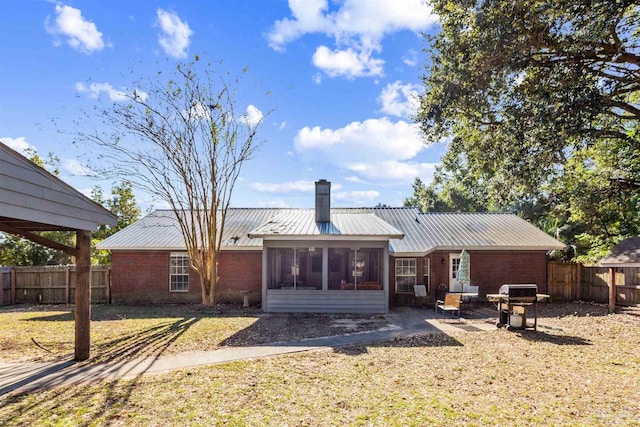 back of property featuring a lawn, a sunroom, and a patio