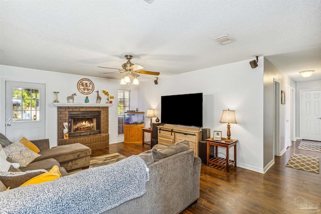 living room featuring a textured ceiling, ceiling fan, dark hardwood / wood-style flooring, and a fireplace