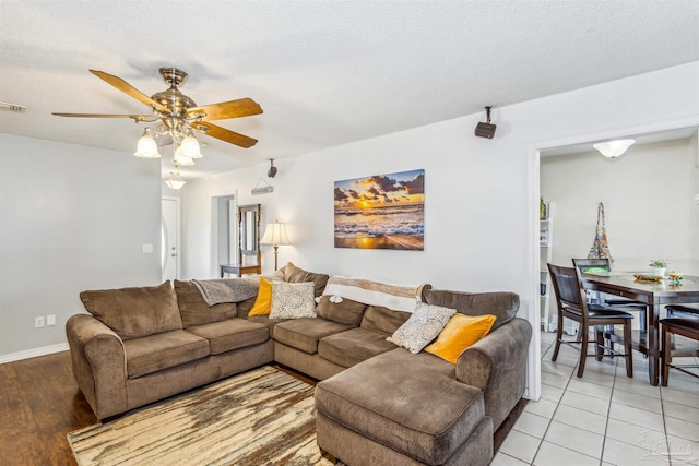 living room featuring ceiling fan, light tile patterned flooring, and a textured ceiling