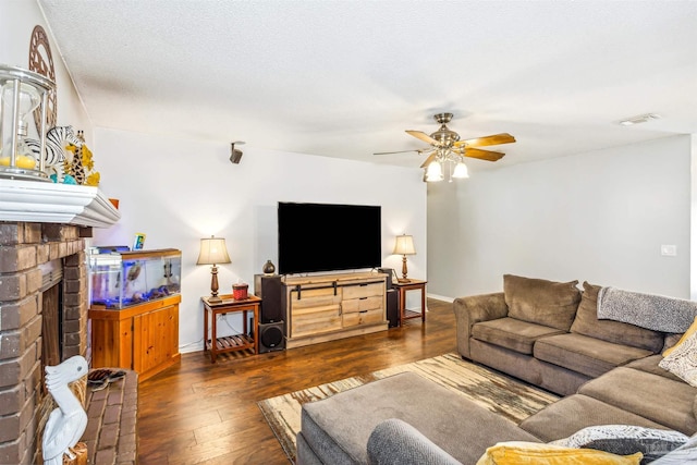 living room with a fireplace, ceiling fan, dark hardwood / wood-style flooring, and a textured ceiling