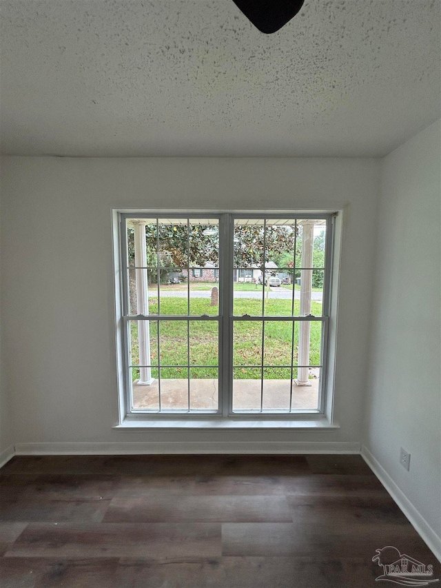 unfurnished room with dark hardwood / wood-style flooring and a textured ceiling