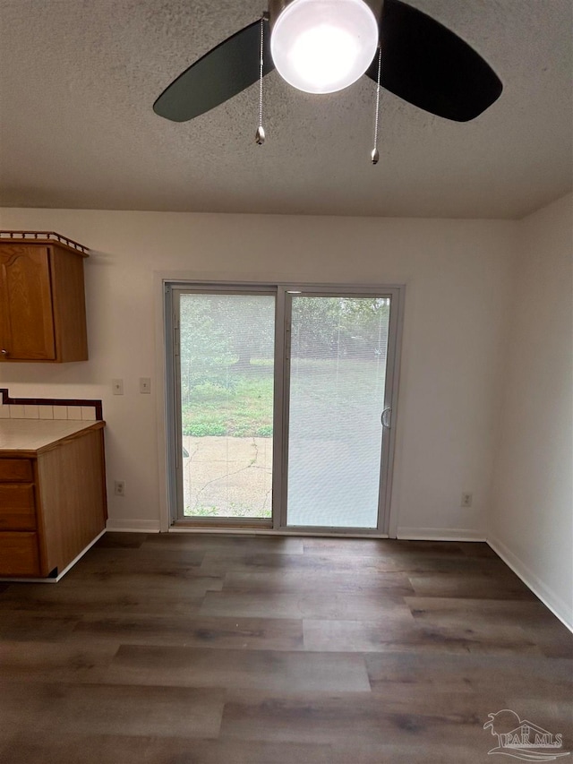 unfurnished dining area featuring wood-type flooring, plenty of natural light, and a textured ceiling