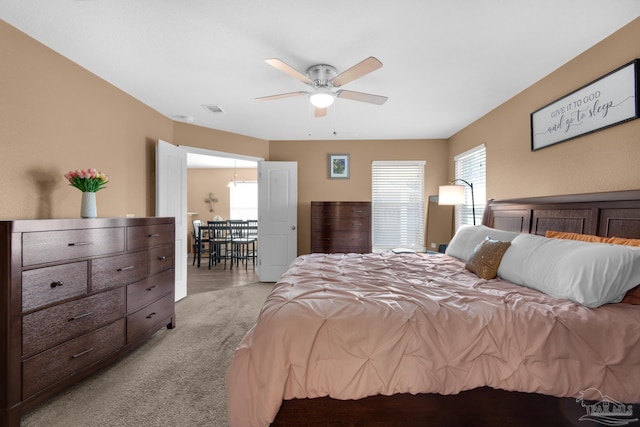 bedroom with visible vents, light colored carpet, and a ceiling fan