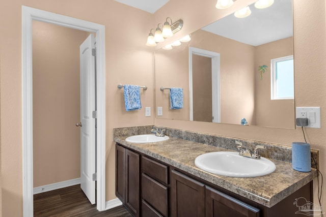 full bath featuring double vanity, wood finished floors, baseboards, and a sink