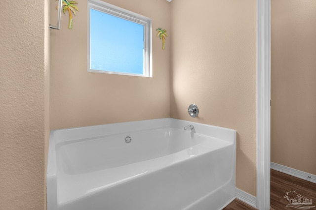 bathroom with baseboards, a garden tub, and wood finished floors