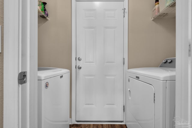 clothes washing area with wood finished floors, laundry area, and washer and clothes dryer