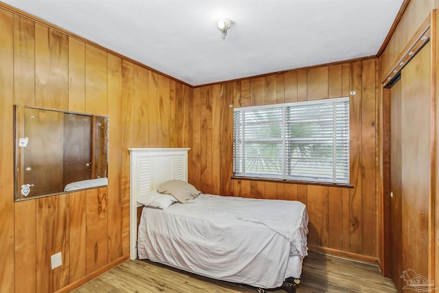 bedroom with ornamental molding, wood walls, and wood-type flooring