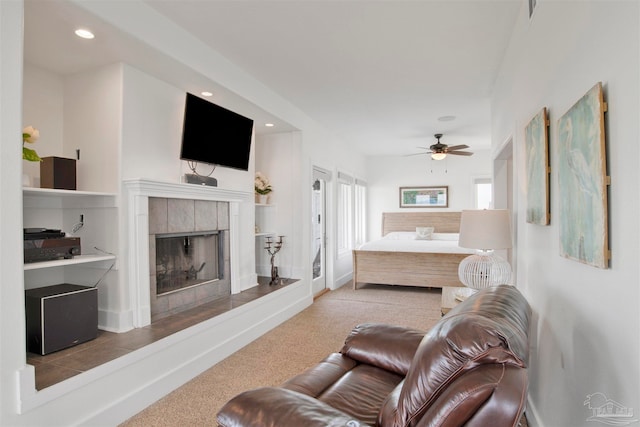 carpeted living room with ceiling fan and a tile fireplace