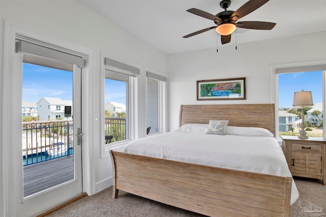 bedroom with ceiling fan, access to exterior, light carpet, and multiple windows