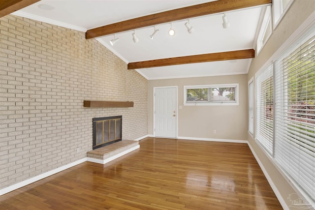1001 E Bobe St, Pensacola, FL 32503 - unfurnished living room featuring a brick fireplace, brick wall, baseboards, rail lighting, and lofted ceiling with beams