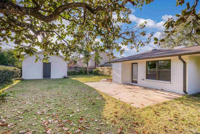 view of yard with fence, an outbuilding, a patio area, and a shed