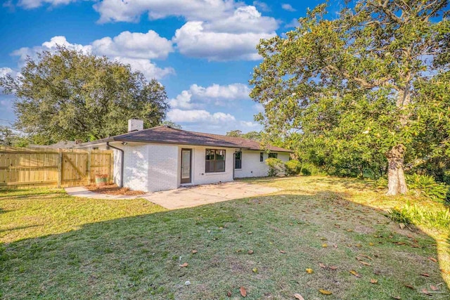 back of property with a chimney, fence, a yard, a patio area, and brick siding
