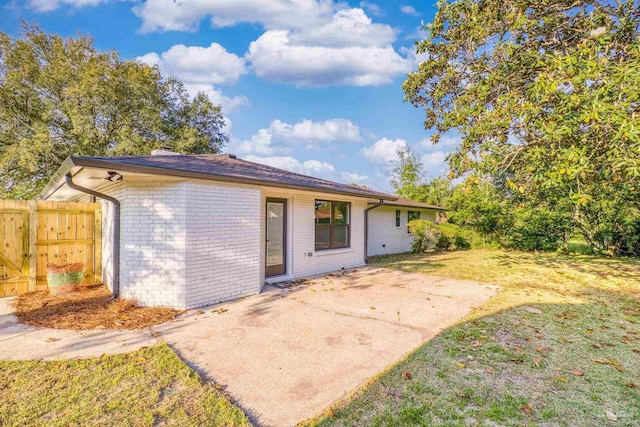 back of house featuring brick siding, a yard, a patio, and fence