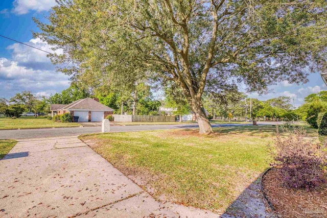 view of yard with fence, an attached garage, and driveway