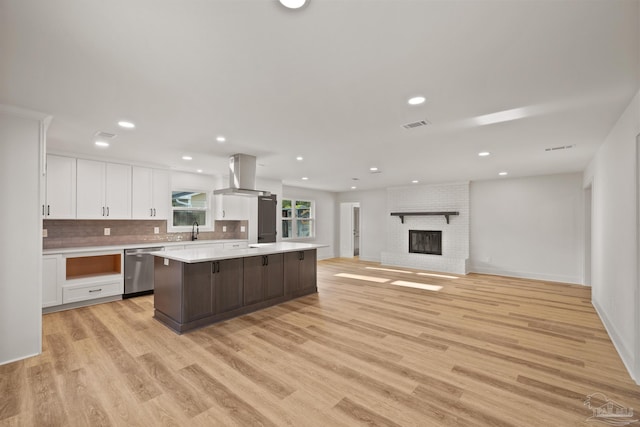 kitchen with white cabinets, exhaust hood, dishwasher, a sink, and a kitchen island