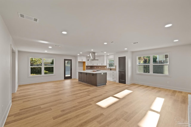 kitchen featuring open floor plan, island exhaust hood, a healthy amount of sunlight, white cabinetry, and visible vents