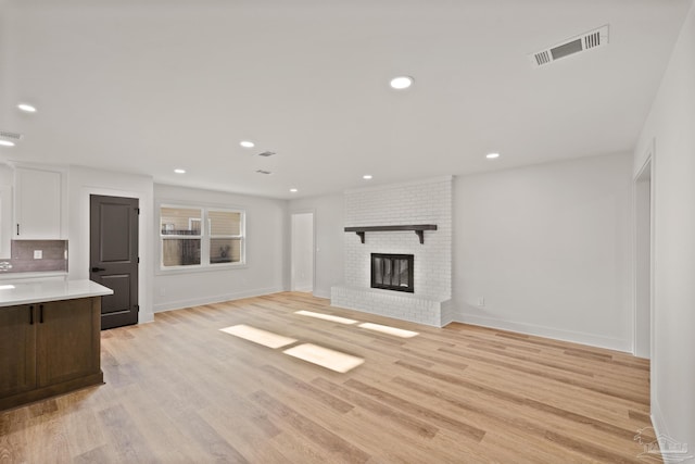 unfurnished living room featuring light wood finished floors, baseboards, visible vents, and recessed lighting