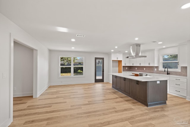 kitchen with island exhaust hood, light wood finished floors, light countertops, visible vents, and white cabinetry
