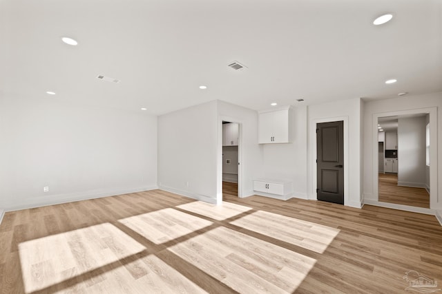 unfurnished living room featuring baseboards, light wood-style floors, visible vents, and recessed lighting
