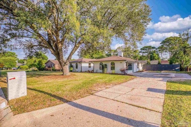 view of front of home with a front lawn, driveway, a chimney, and fence