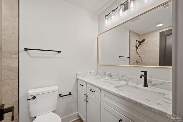 bathroom featuring toilet, vanity, visible vents, and tiled shower