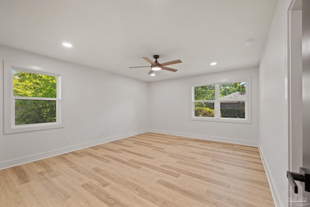unfurnished room with a ceiling fan, baseboards, a wealth of natural light, and light wood-style floors