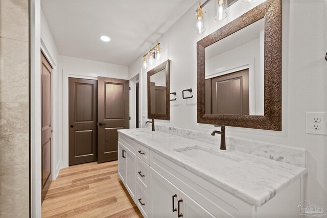full bathroom with wood finished floors, a sink, recessed lighting, and double vanity