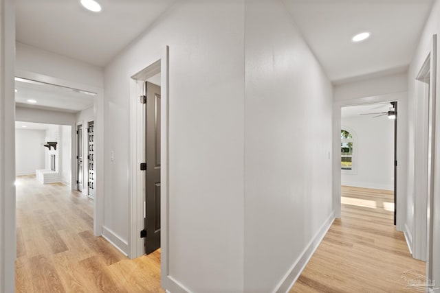 hall with baseboards, recessed lighting, and light wood-style floors