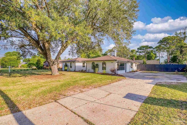 view of front facade featuring fence, a chimney, a front yard, and concrete driveway