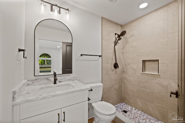 full bathroom featuring tiled shower, vanity, recessed lighting, and toilet